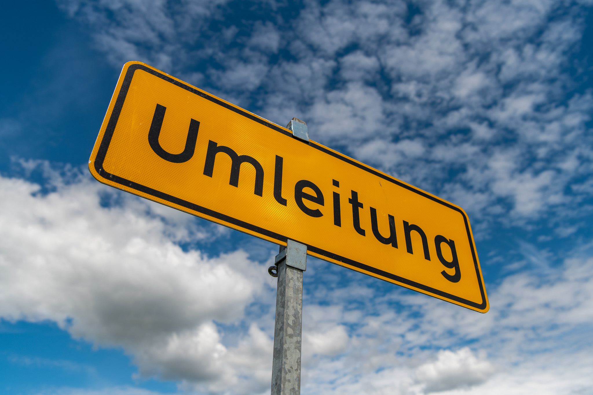 Das Foto zeigt ein gelbes Schild mit der Aufschrift Umleitung