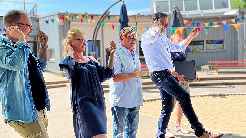 Auf dem Bild sind fünf Erwachsene beim Tanzen zu sehen. 