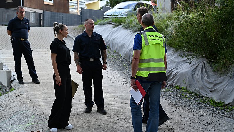 Auf dem Bild sind 5 Personen zu sehen die sich unterhalten. 