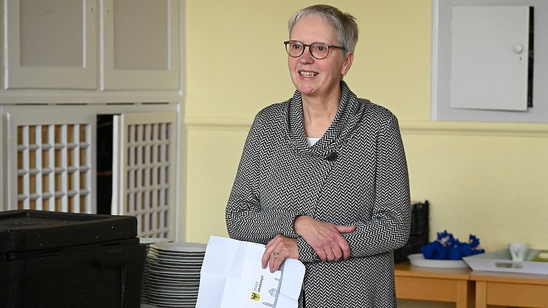 Auf dem Bild ist eine Frau zu sehen, die einen Briefumschlag in den Händen hält. 