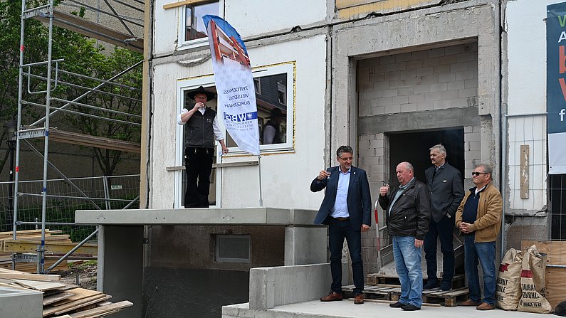 AUf dem Foto sind mehrere Personen zu sehen. Das Foto wurde während eines Richtfestes aufgenommen. 