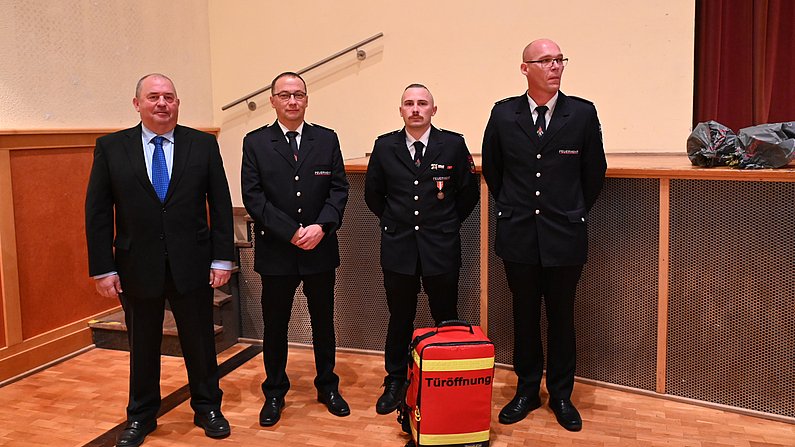 Auf dem Bild sind vier Personen zu sehen. Sie präsentieren einen Türöffnungsrucksack. 