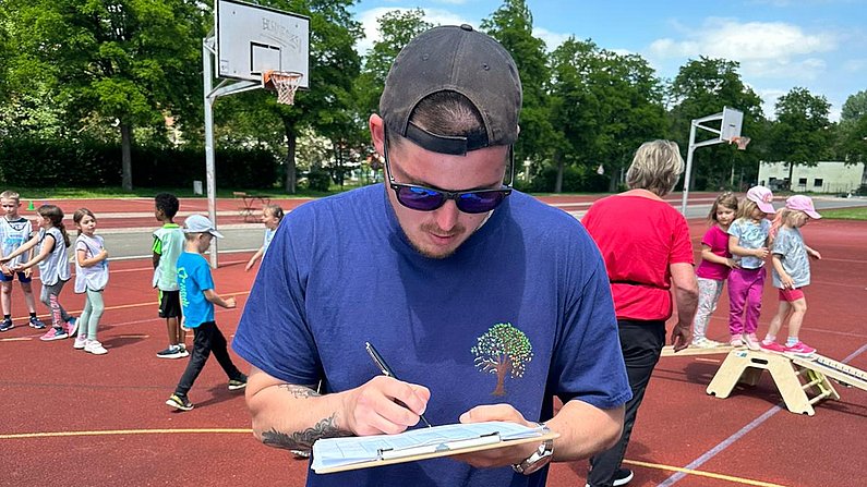 Auf dem Bild ist ein Erzieher beim Sportfest zu sehen. 