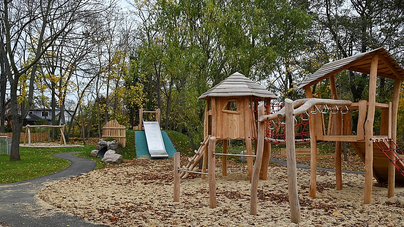 Auf dem Bild ist der Garten der neuen Kita Weltentdecker zu sehen. Hier ist ein Holzspielturm zu sehen.