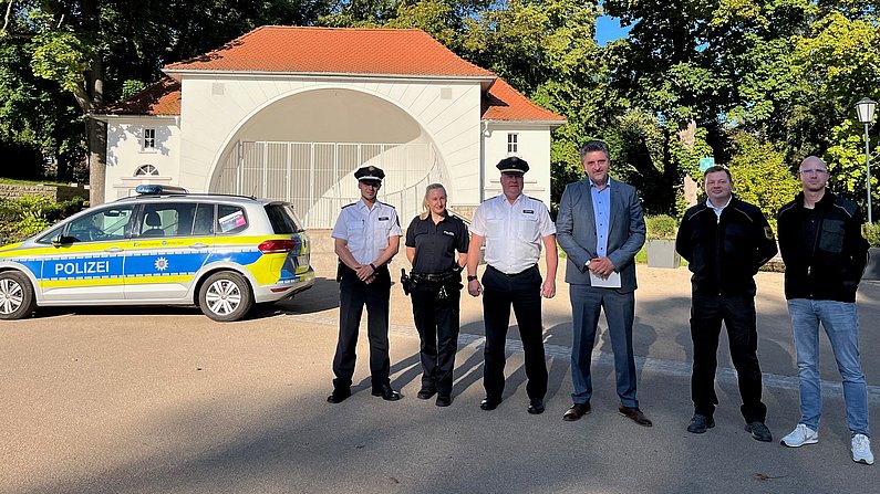 Auf dem Bild sind sechs Personen zu sehen, die vor der Musikmuschel (Schlossgarten) in Arnstadt stehen. 