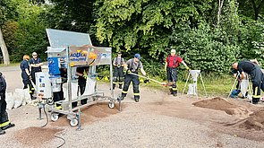 Auf dem Bild ist ein Sandsackfüllmaschine im Einsatz zu sehen. 